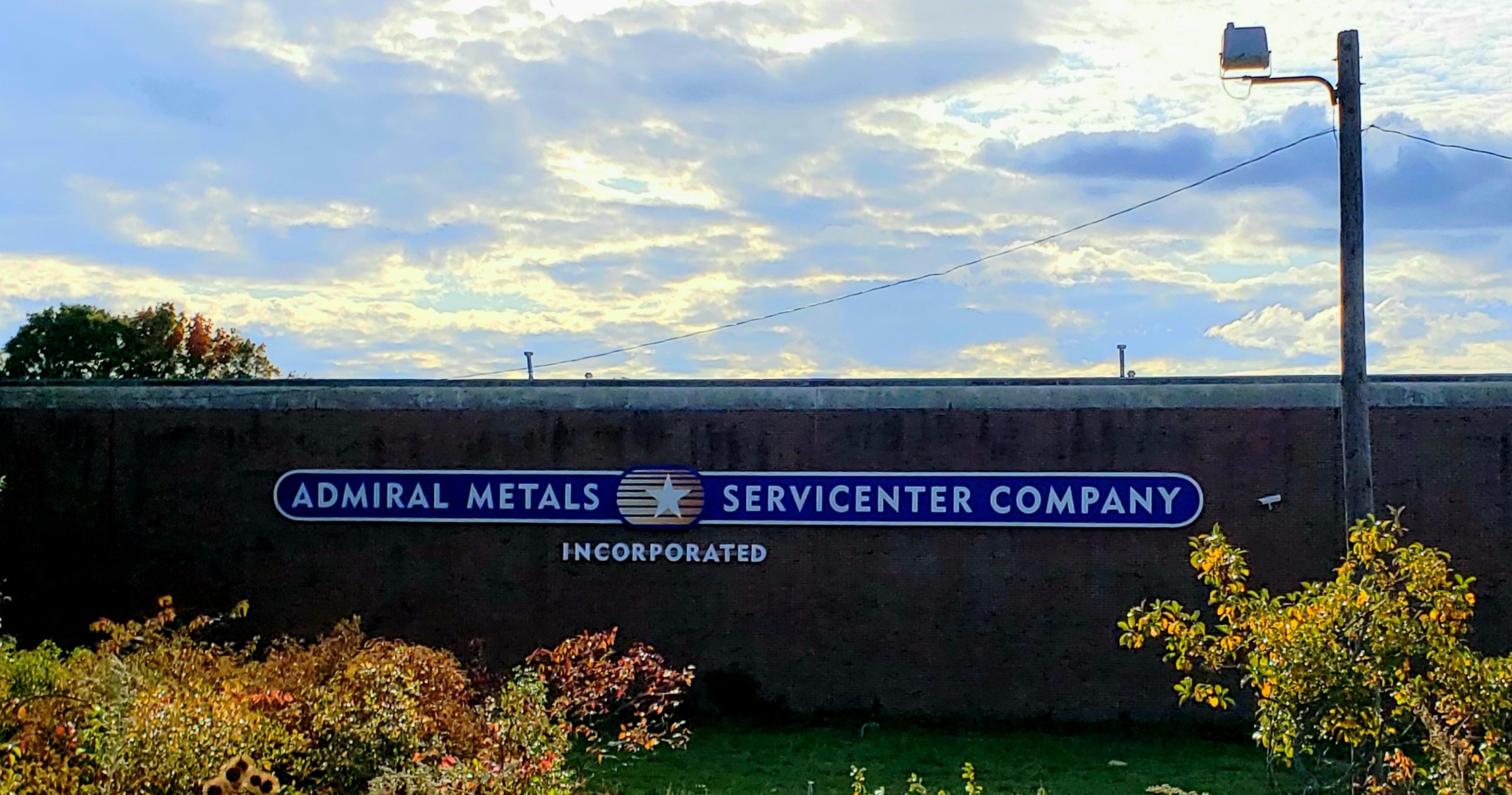 Admiral Metals Sign with light sunset and fall trees.